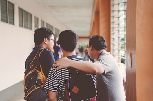 Group of male teenagers walking in a school corridor with backpacks, bonding and chatting.