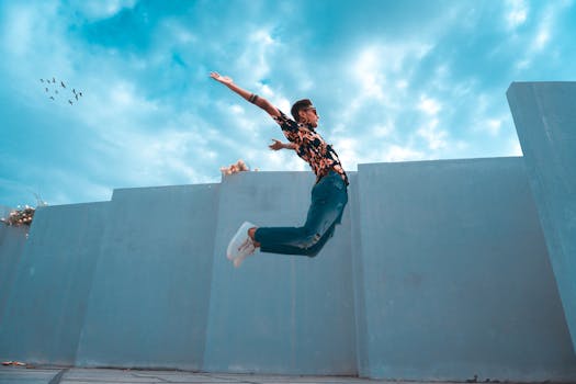 Man stylishly jumping with cloudy background, showcasing fashion and energy.